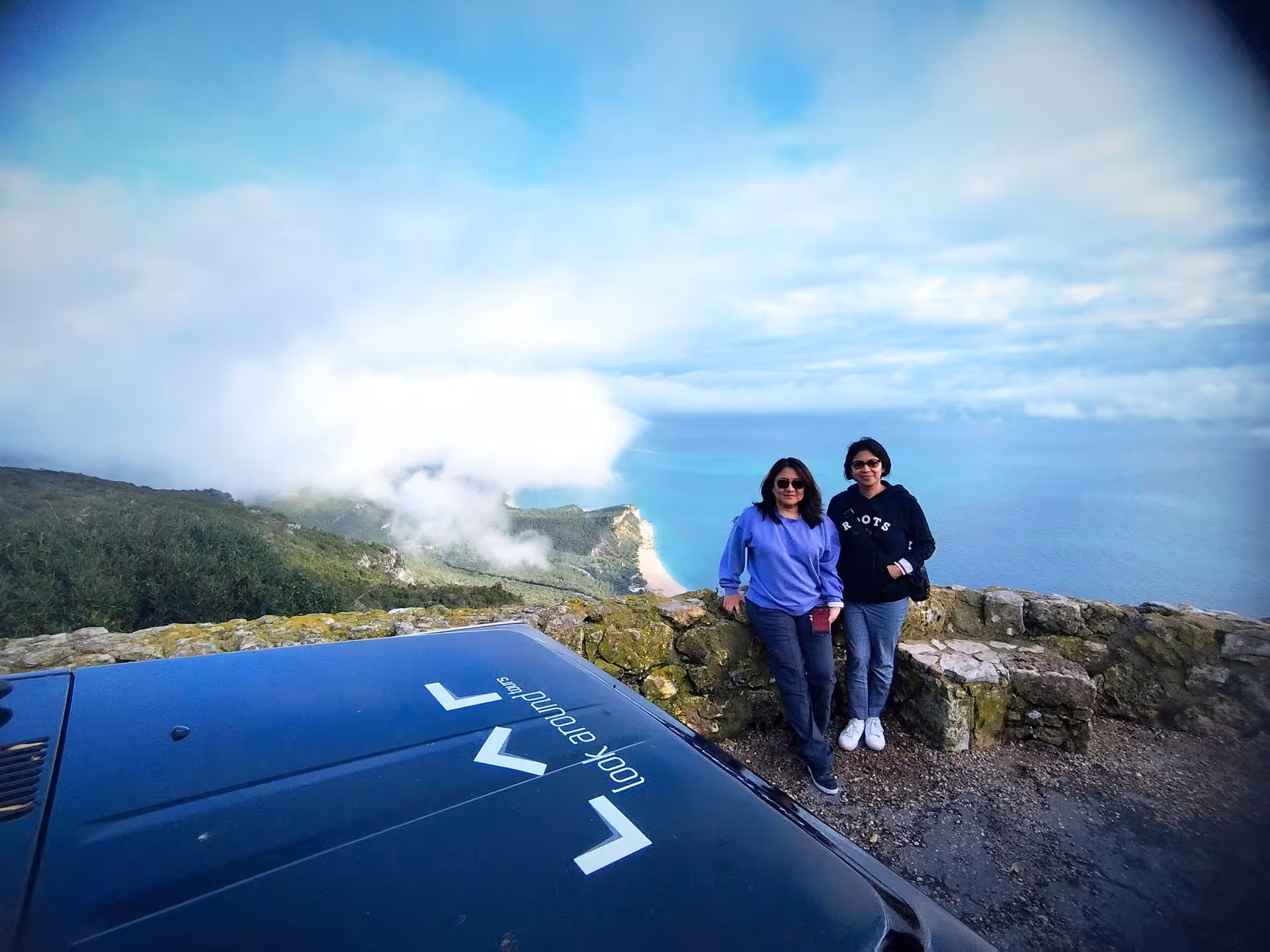 Guests at Arrábida viewpoint stop on 4x4 safari tour, with dramatic cliffs, clouds and blue Atlantic panorama