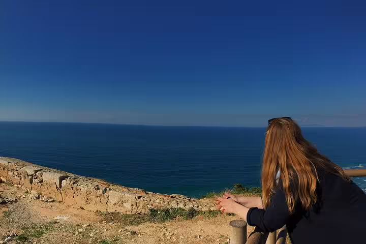 Scenic coastal view from Arrabida with a tourist enjoying the blue ocean vistas on a private day tour from Lisbon.