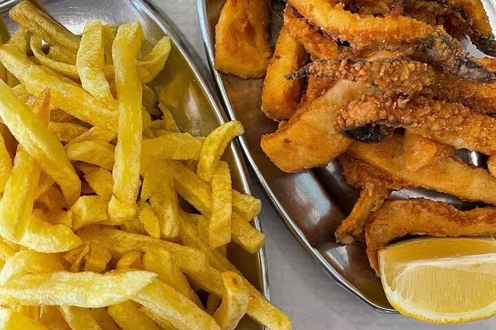 Delight in local Portuguese cuisine with crispy fried fish and golden fries, a highlight of the Arrábida & Sesimbra day trip.