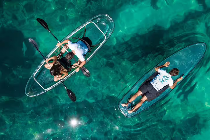 Aerial view of people kayaking in transparent kayaks over clear blue waters on an Arrábida guided tour adventure.