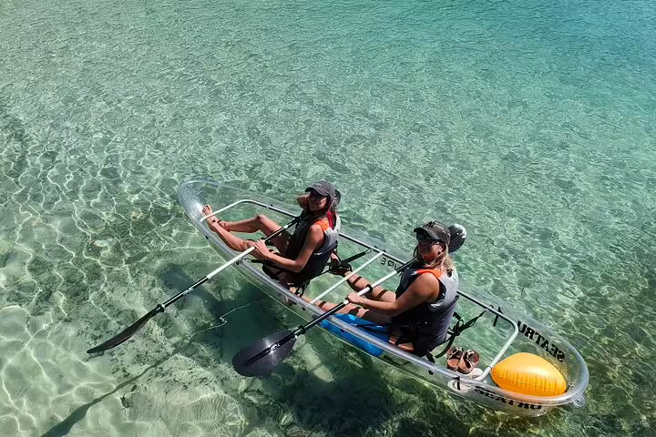 Two people enjoying a guided transparent kayaking tour on crystal-clear waters in Arrábida, showcasing marine life below.