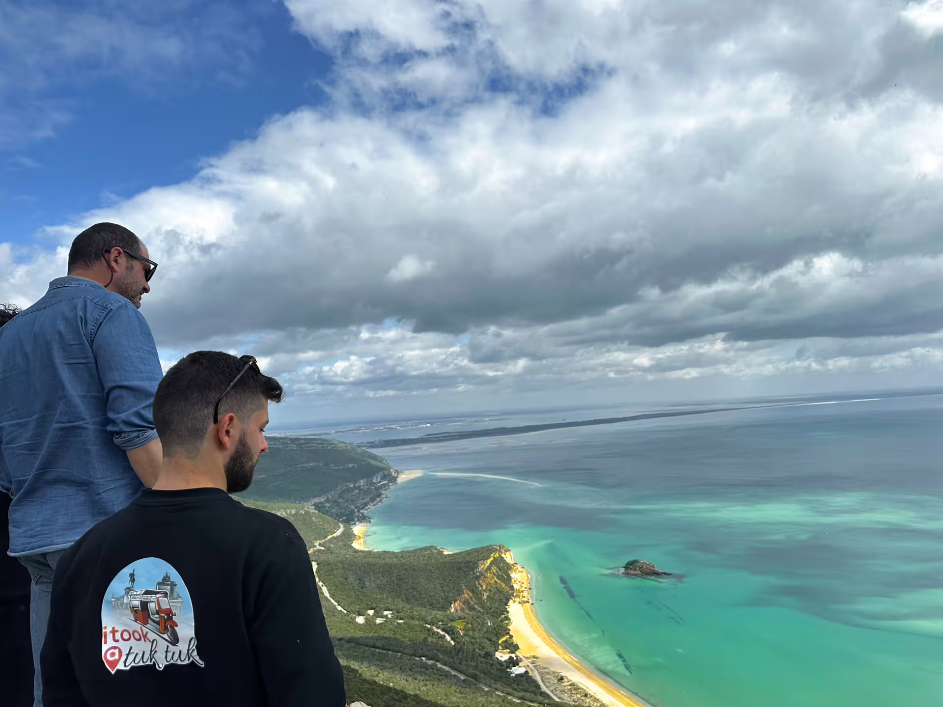 Tourists enjoying a stunning panoramic view of the Blue Coast from Arrábida's scenic cliffs.