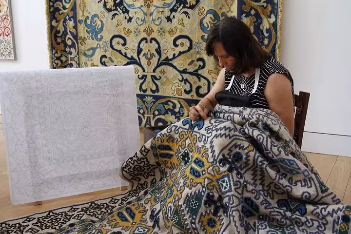 Artisan weaving a traditional Arraiolos rug, demonstrating local craft techniques on a private walking tour.