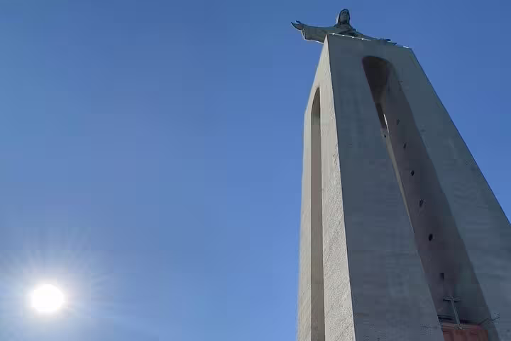 Monumental statue with outstretched arms against a clear blue sky, capturing serene beauty on the Arrábida & Sesimbra tour.