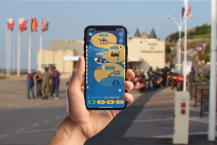 Hand holding smartphone with D-Day tour mobile game map app in Arromanches, France