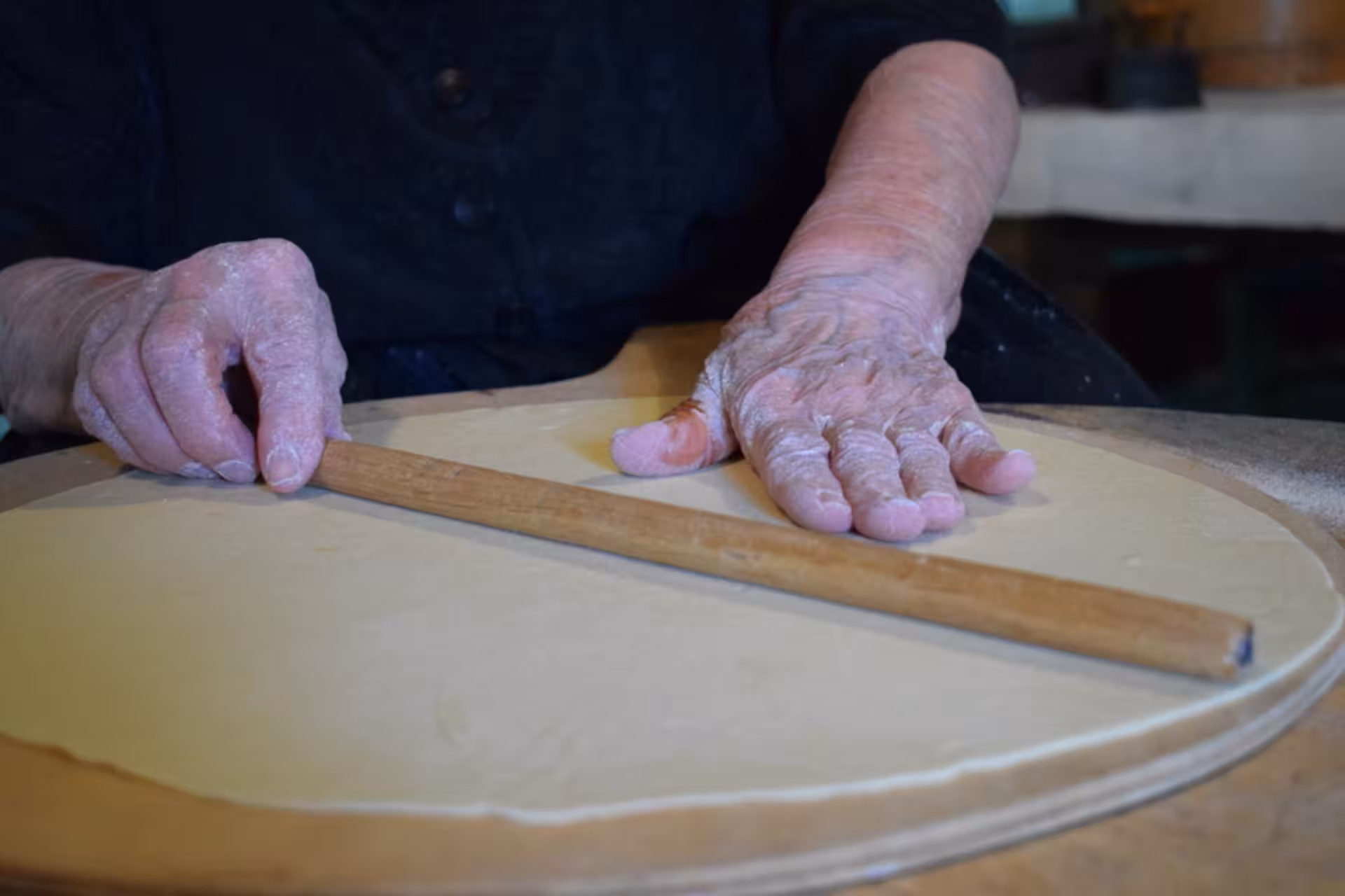 Hands of an artisan shaping traditional carasau bread dough in an Orgosolo workshop, highlighting Sardinian culture.