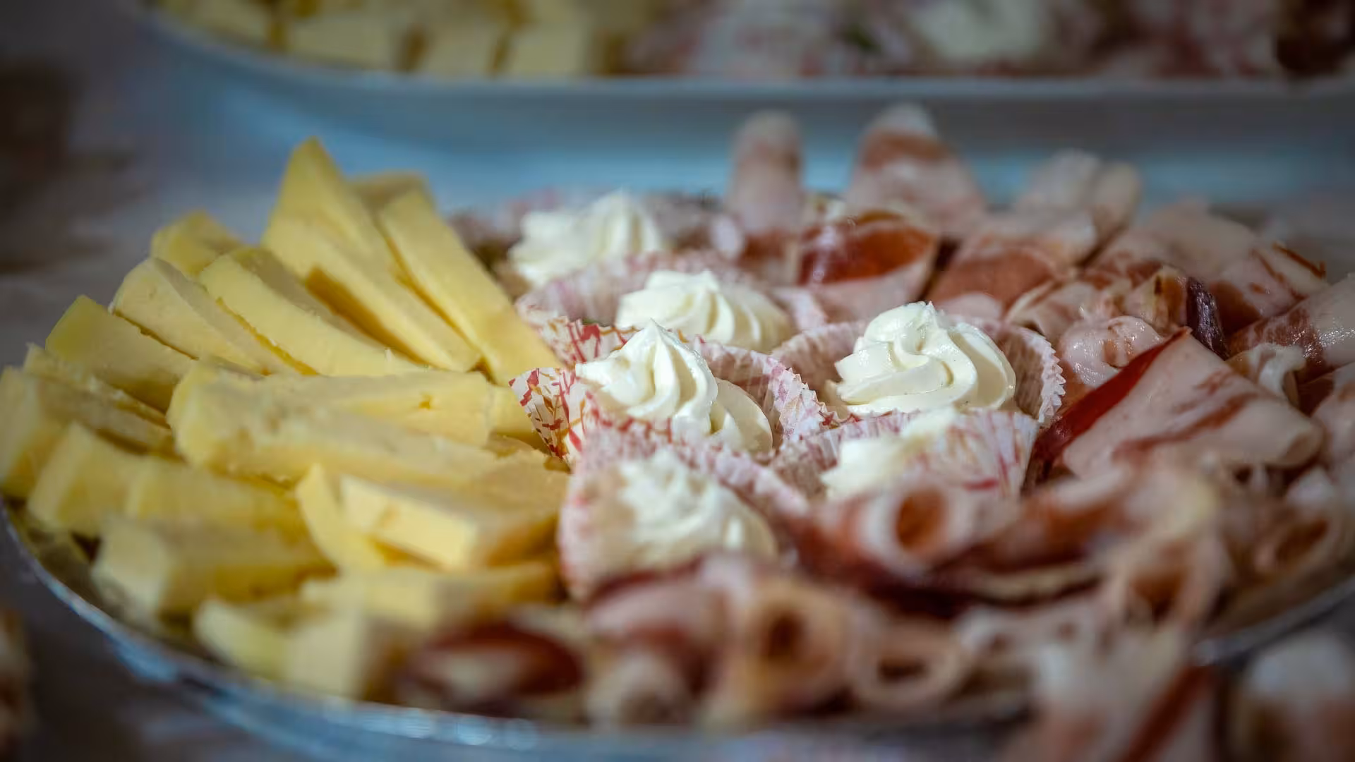 Platter of sliced cheese and cured meats with creamy toppings for Arzana shepherd farm lunch experience.