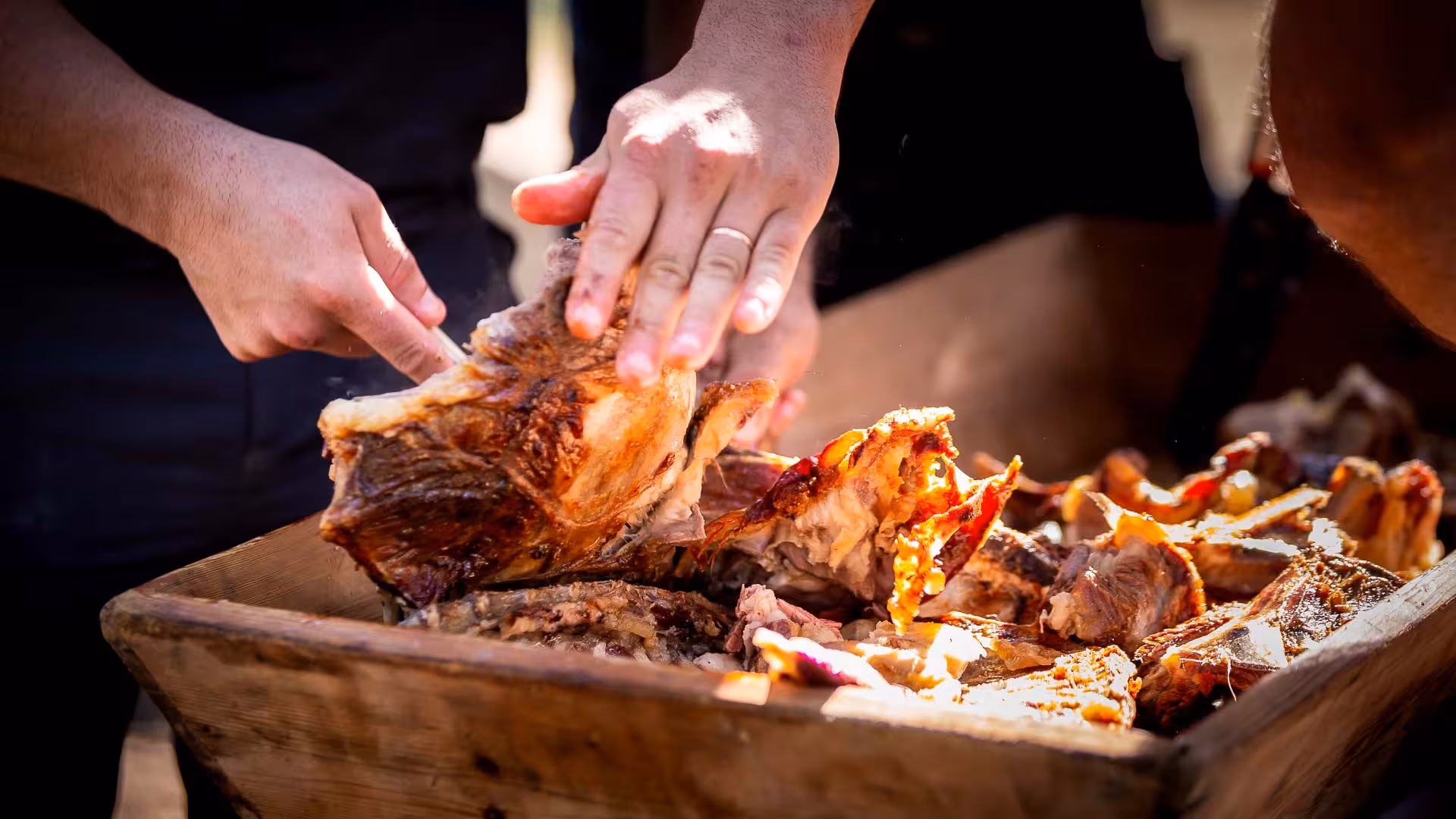 Hands preparing roasted meat during the Arzana shepherd farm culinary tour experience.