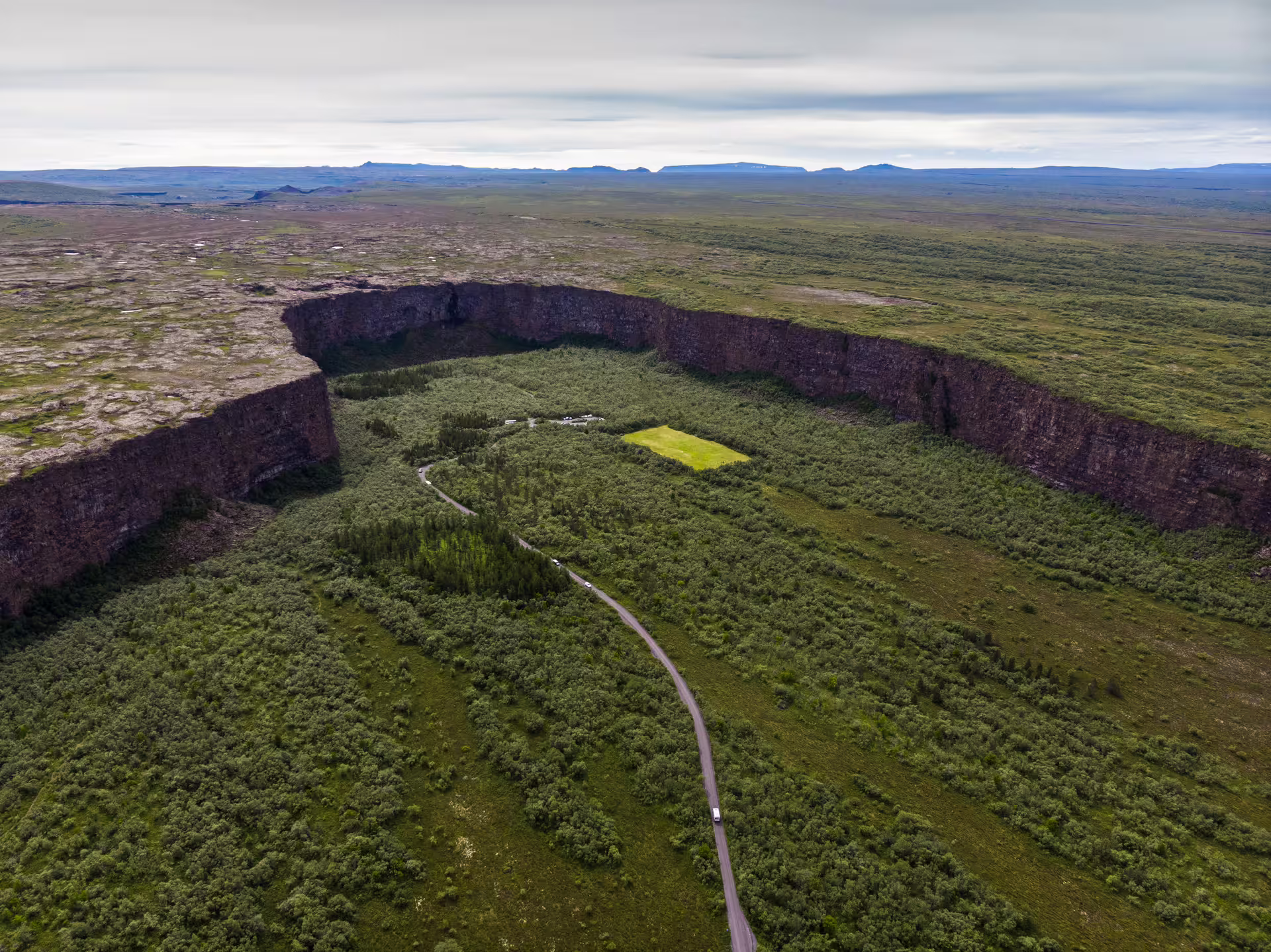Aerial view of Ásbyrgi canyon with lush green vegetation and winding road in North Iceland