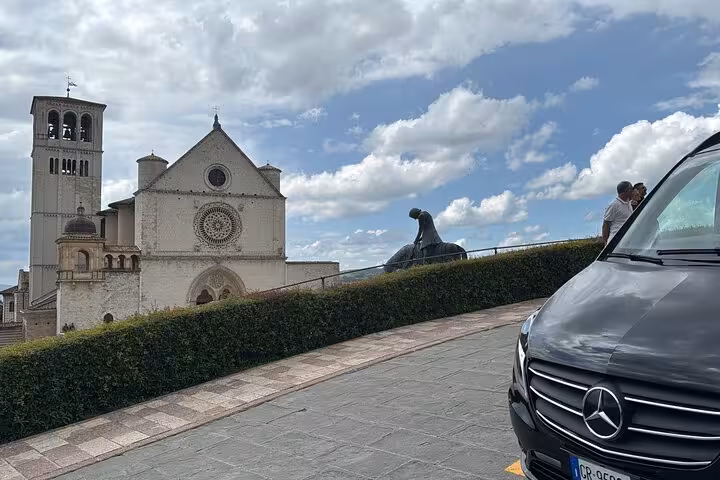 View of the Basilica of Saint Francis of Assisi with a parked luxury vehicle on a private day tour from Rome.