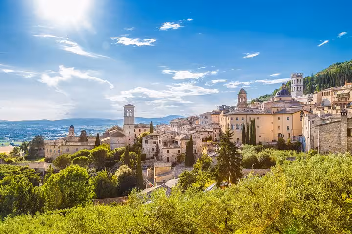 Charming hillside view of Assisi's historic architecture set against a vibrant landscape and clear skies.