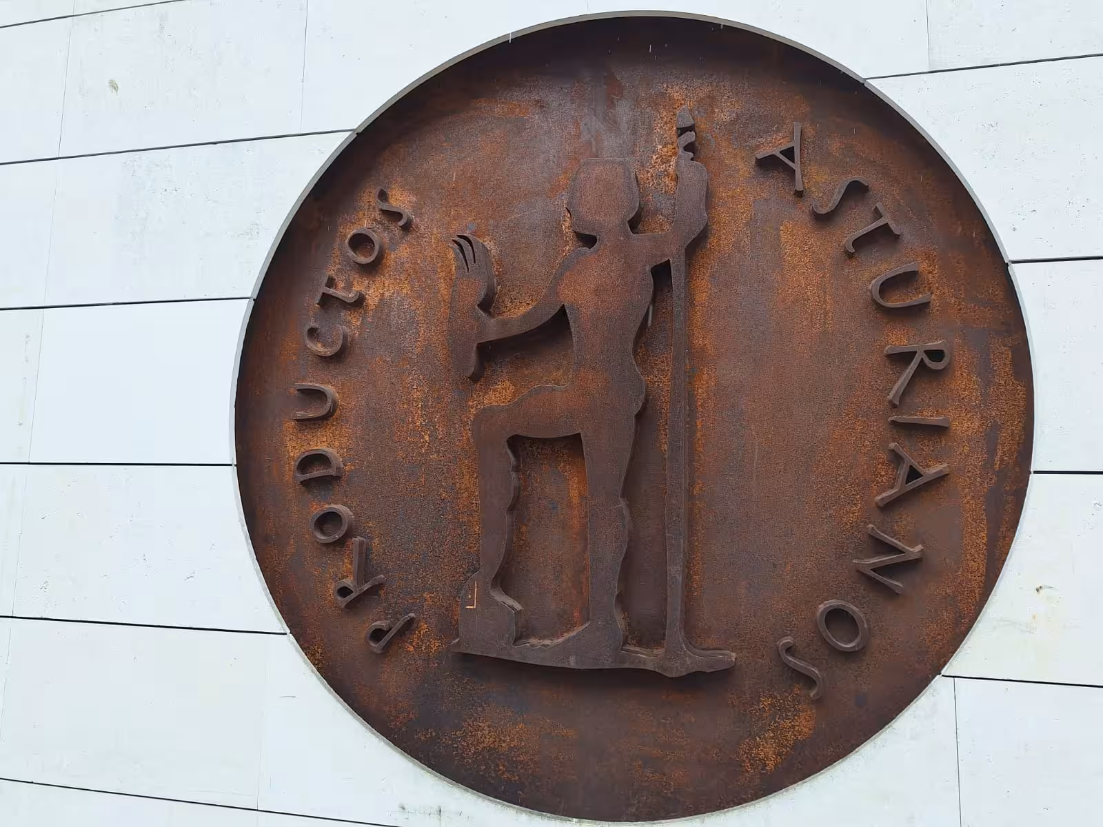 Rustic Asturian metal plaque on a wall, representing traditional culture on the Oviedo food and wine tour.