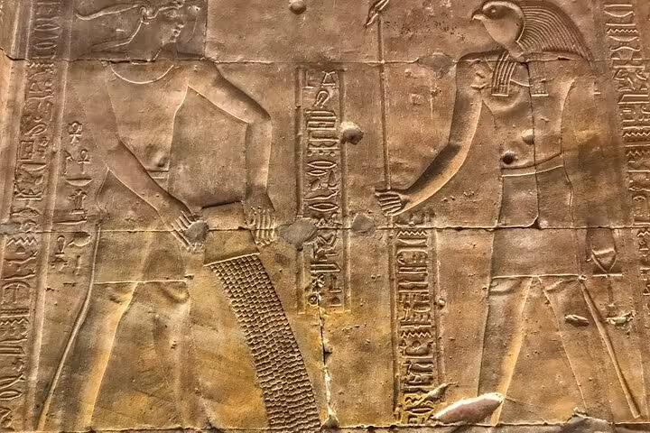 Ancient Egyptian temple relief with hieroglyphs in Aswan, featured on private day tour from Luxor
