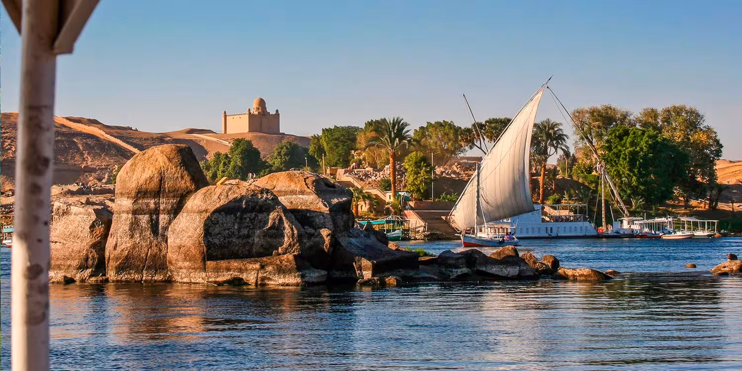 Aswan Nile felucca sailing past granite rocks and palm-lined islands, perfect add-on to a Nubian Museum tour