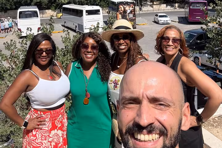 Smiling group selfie with private guide on Athens Acropolis city tour, with tour buses and streets below