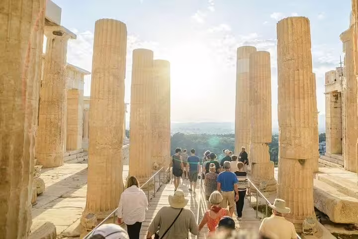Visitors walk through Acropolis columns at sunset on a private Athens walking tour with Plaka food tastings