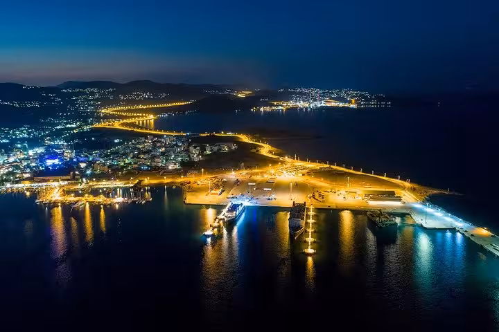 Night aerial of Athens waterfront and port lights, smooth private luxury transfer from Athens hotels to Athens airport