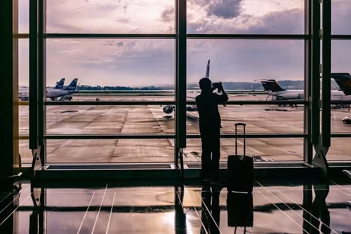 Traveler with suitcase at Athens Airport window, perfect for pre-booked luxury private transfer to Athens hotels