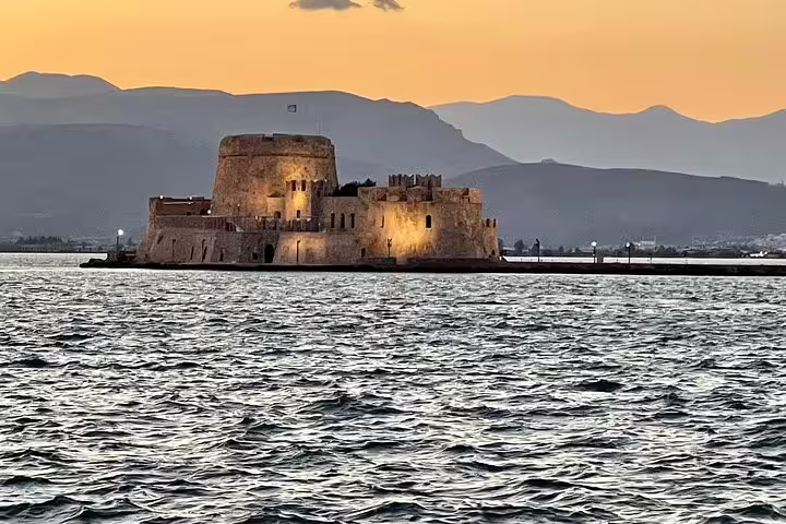 Sunset view of Bourtzi Castle in Nafplio harbor, scenic detour on private Athens Airport to Piraeus transfer