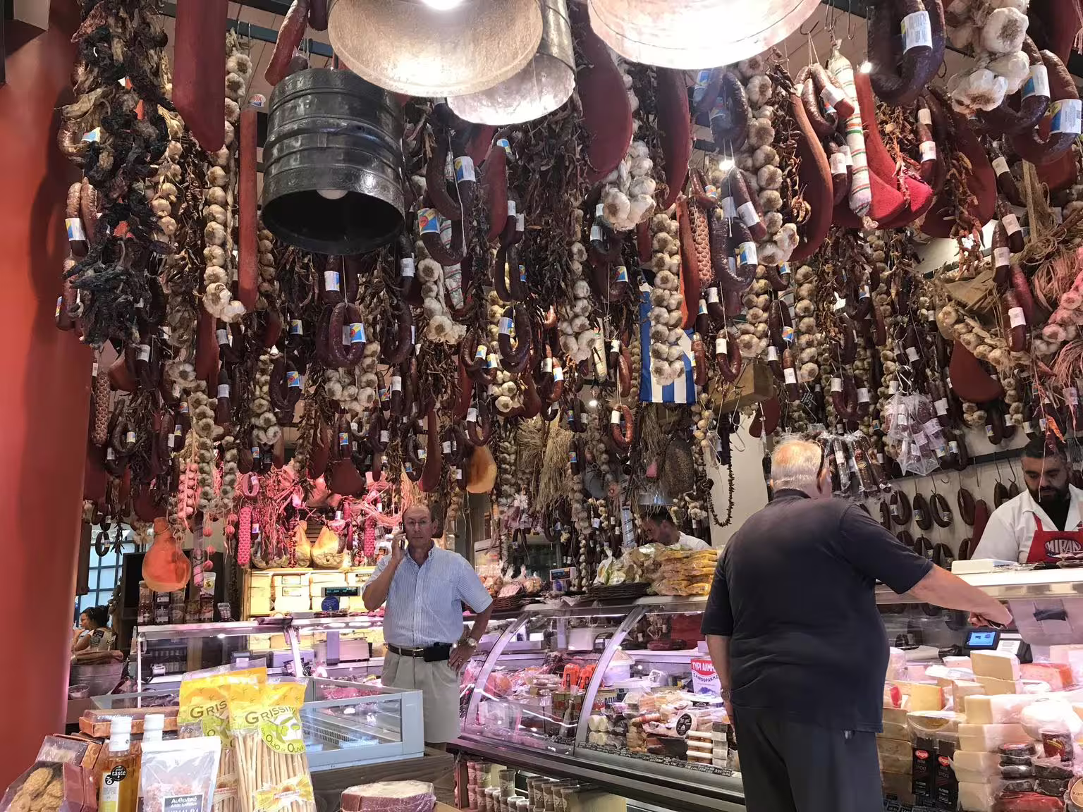 Athens Central Market deli with hanging cured sausages and garlic, a stop on a gourmet food walking tour