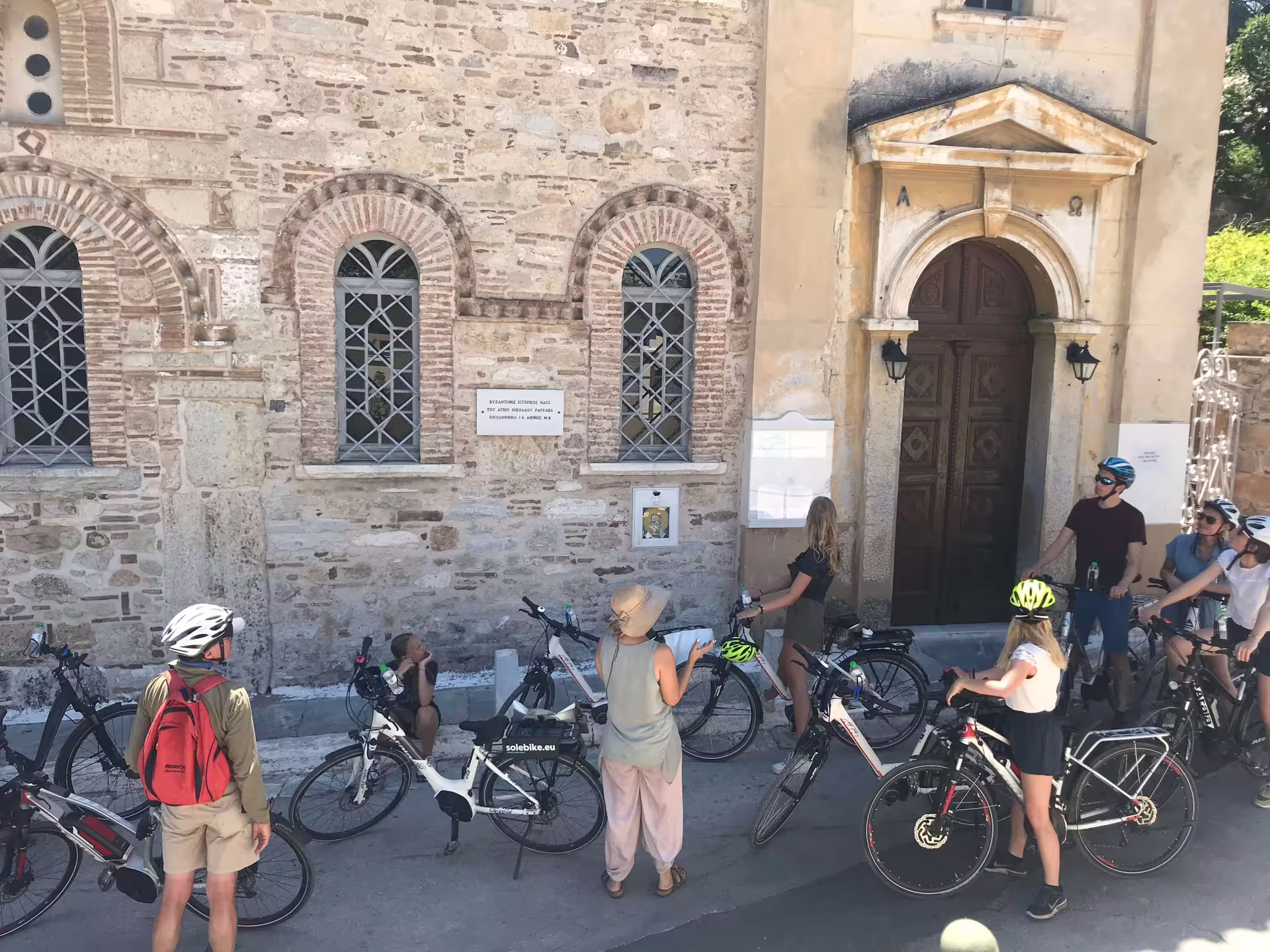 Tour group with bicycles outside a historic building in Athens, exploring classical architecture on a guided tour.