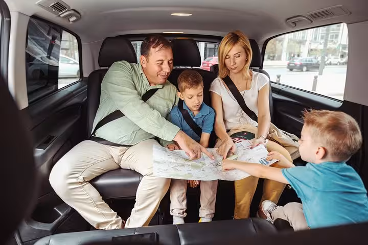 Family riding in private car from Athens to Corinth Canal, planning route for wine tasting and pottery workshop tour
