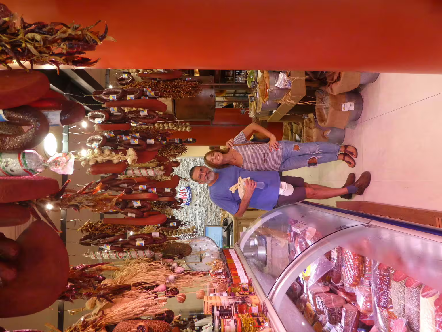 Guests at Athens Central Market deli with hanging cured sausages, a highlight of the gourmet food walking tour