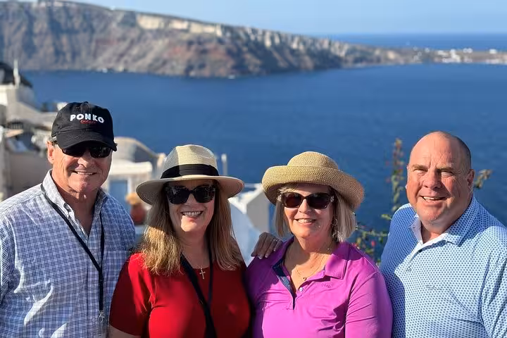 Travelers posing with Santorini caldera views on 7-day Athens Mykonos and Santorini island-hopping tour