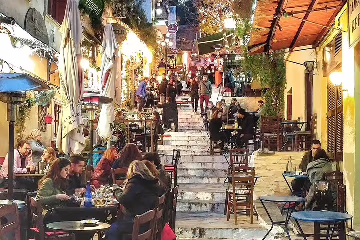 Lively Athens night scene on Plaka steps with tavernas and diners, part of a small-group walking tour dinner