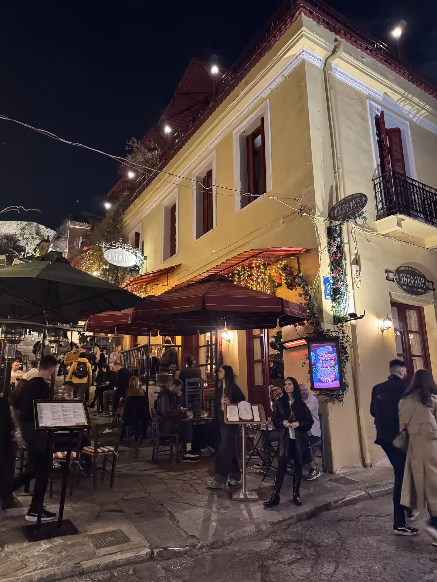 Lively Athens night walk past a cozy Plaka taverna, ideal stop on a walking and wine tasting tour