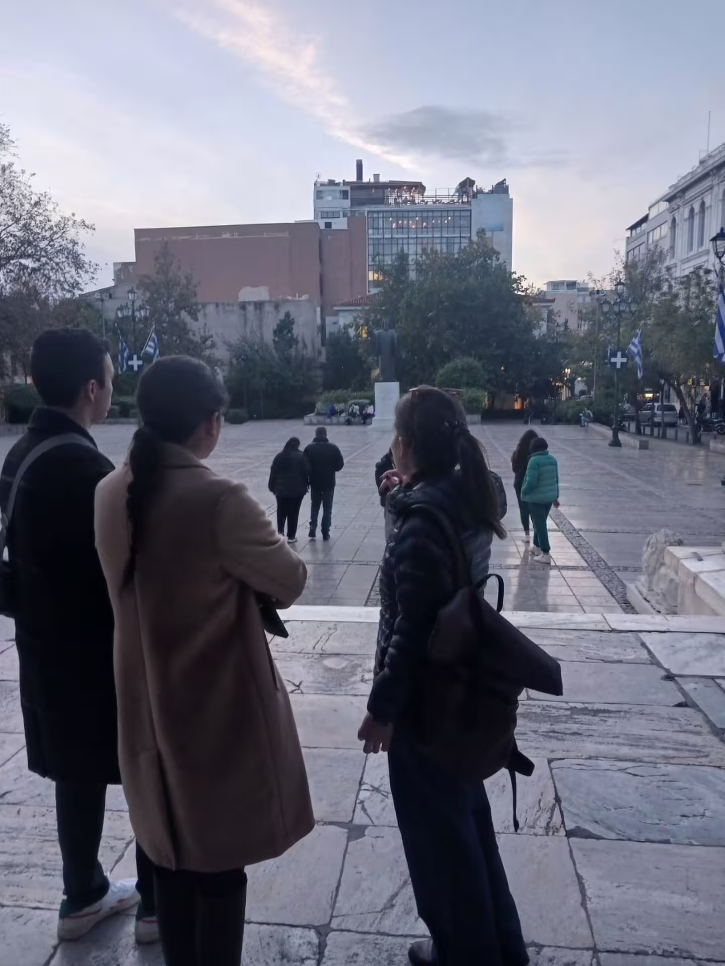 Small group in Syntagma Square at dusk, starting an Athens at night walking tour with local dinner experience