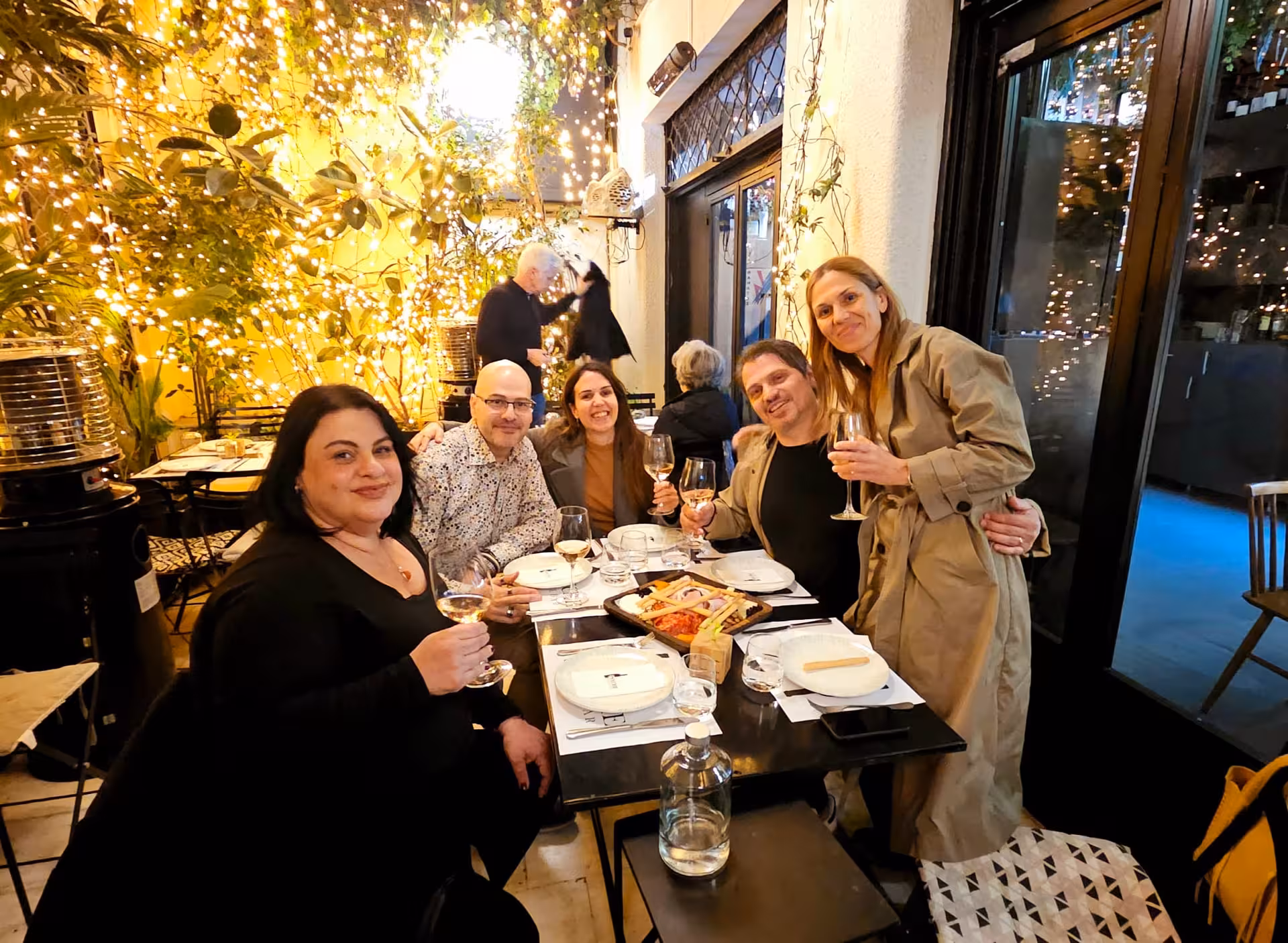 Friends toast Greek wine at a twinkling Athens courtyard taverna during an evening walking tour and tasting