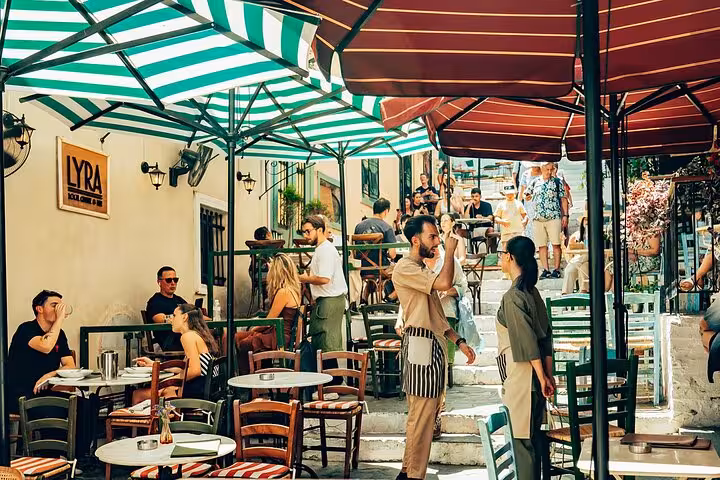 Outdoor cafe in Athens Plaka with umbrellas and locals dining during a small group walking tour and Greek tastings