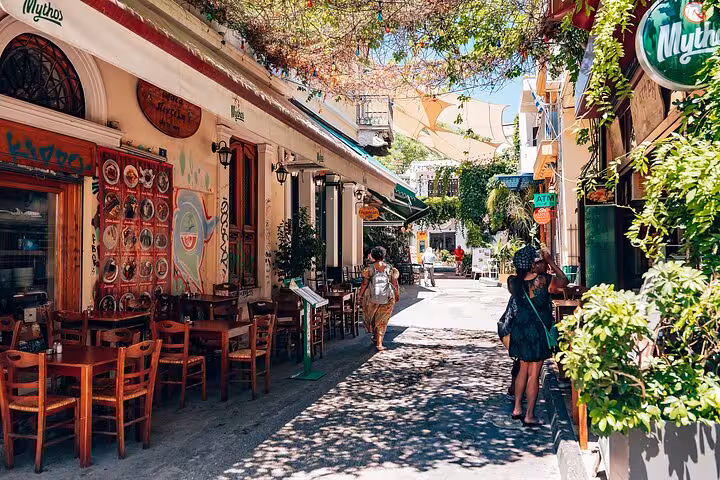 Athens Plaka alley with traditional tavernas and shaded tables on a small group walk and Greek food tasting tour