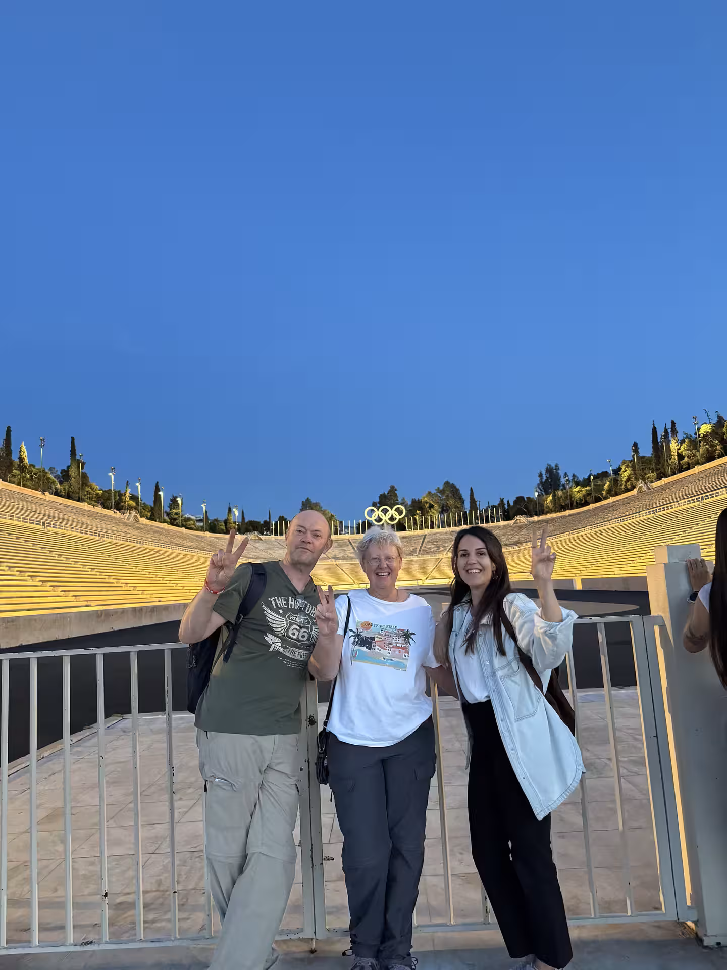 Happy travelers at Panathenaic Stadium on a private Athens tour by car, posing with Olympic rings backdrop