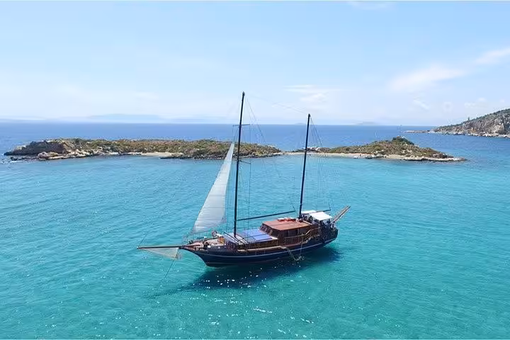 Traditional sailing yacht on Athens all-day Saronic Gulf cruise, anchored in turquoise sea near a small islet