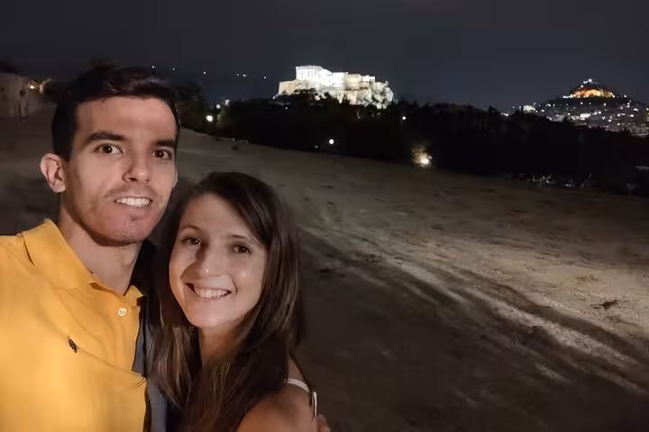 Couple smiling at night with illuminated Acropolis of Athens in background