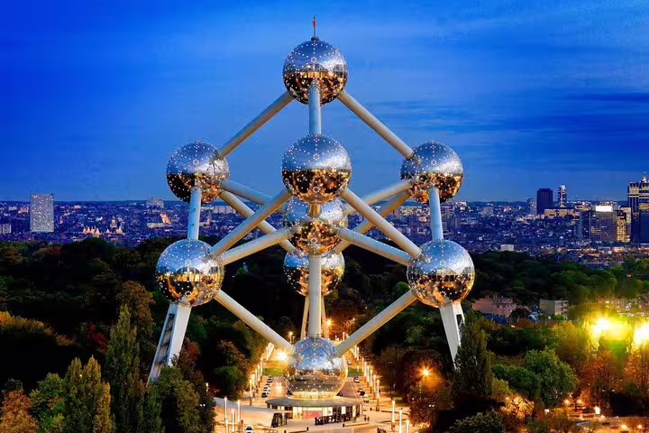 Atomium Brussels illuminated at dusk with city skyline in background