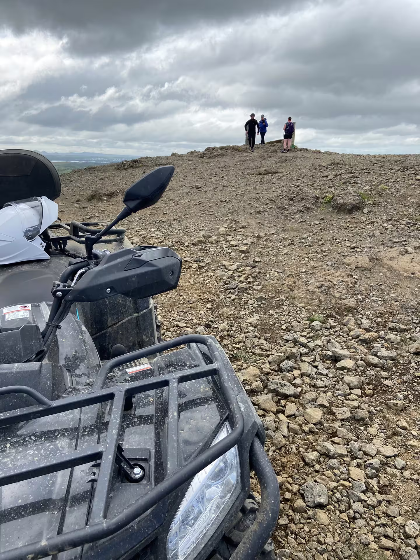 ATV quad bike parked on rocky hilltop in Reykjavik with three hikers enjoying scenic views