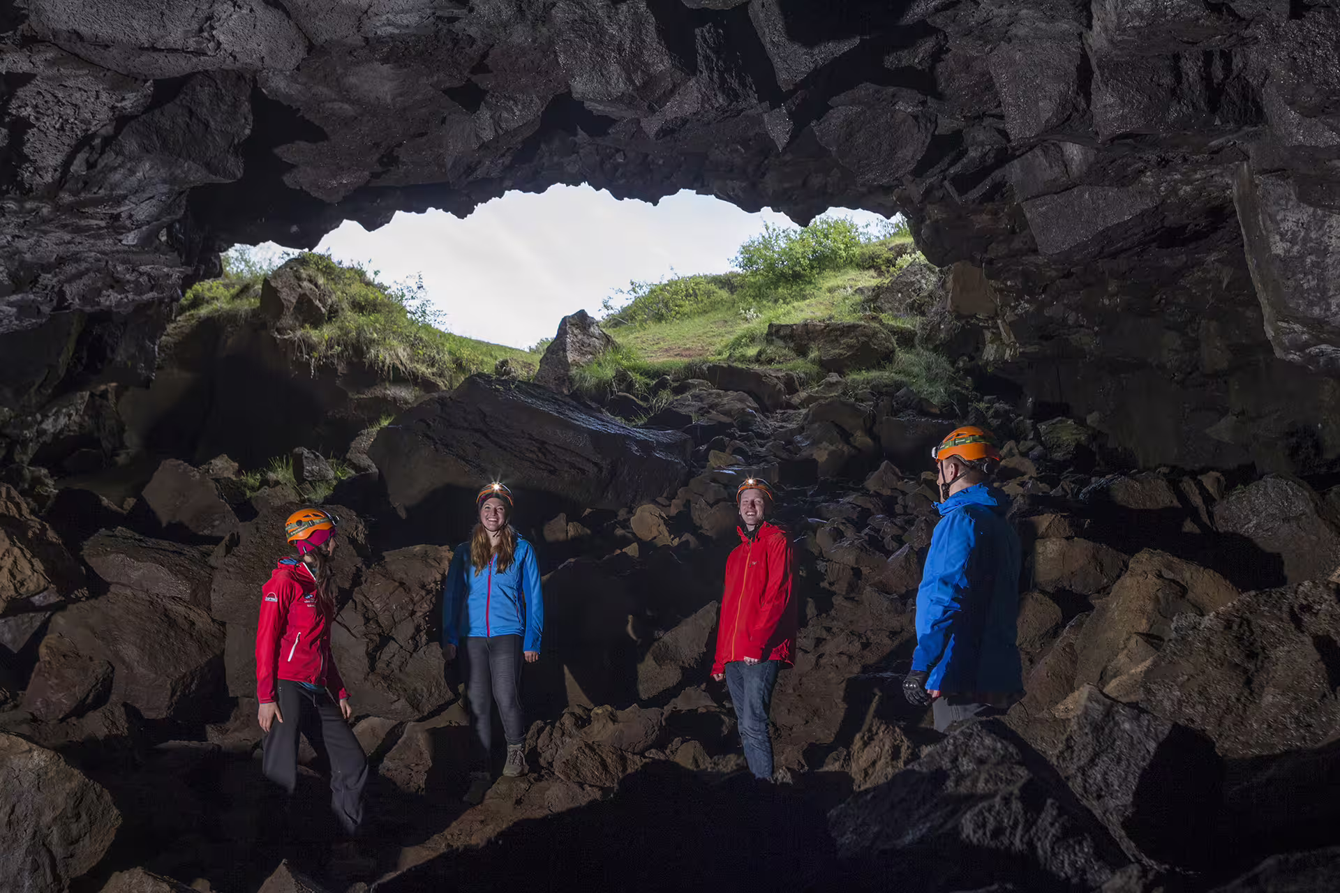 Adventure seekers explore a rocky cave entrance during an exhilarating ATV and caving tour, wearing helmets and outdoor gear.