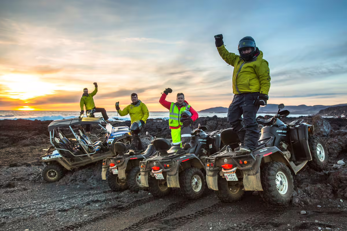 Group of riders celebrating on Can-Am ATVs at black lava beach in Iceland during sunset