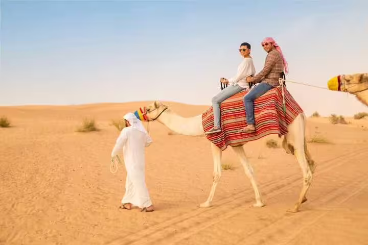 Tourists riding a camel across Sharm El Sheikh desert dunes, part of ATV quad bike adventure and Bedouin dinner