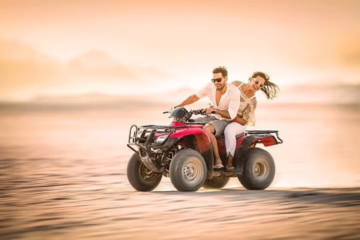 Couple riding ATV quad bike across Hurghada desert at sunset on safari adventure tour with camel ride option