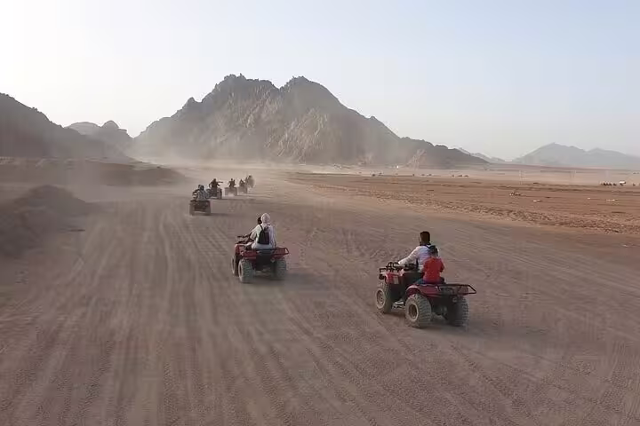 Group ATV quad bike safari from Hurghada speeding across sandy desert track toward rugged mountains