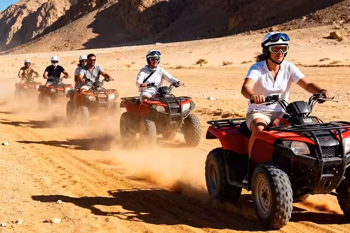 Group ATV quad bike safari in Sharm El Sheikh racing through Sinai desert, kicking up sand on off-road trail
