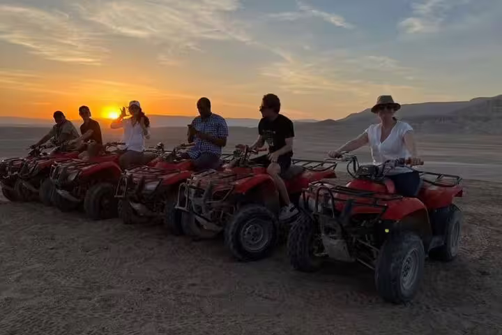 Sunset ATV quad bike adventure in Sharm El Sheikh desert with riders lined up on red quads before Bedouin camp