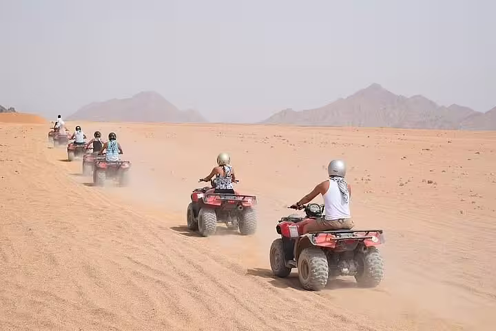 Group ATV quad bikes racing across Hurghada desert dunes on safari adventure tour with mountain backdrop