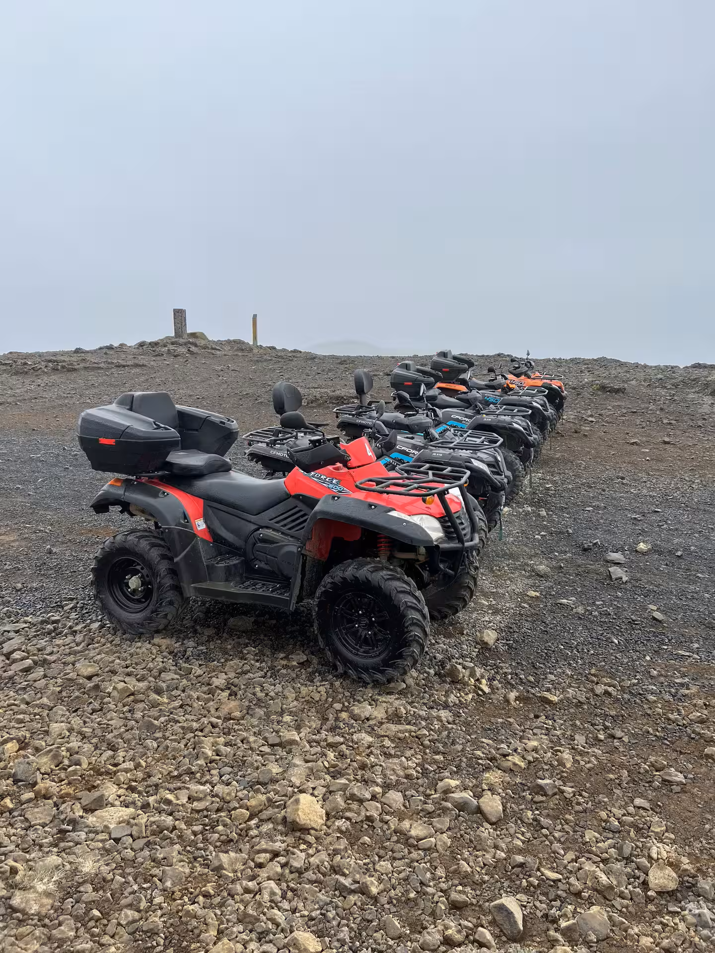 Row of colorful ATVs parked on rocky volcanic terrain under overcast skies in Reykjavik, Iceland