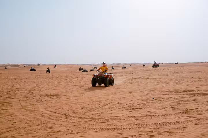 ATV quad riders crossing wide Sahara sand dunes on Marsa Alam sunset desert safari adventure tour