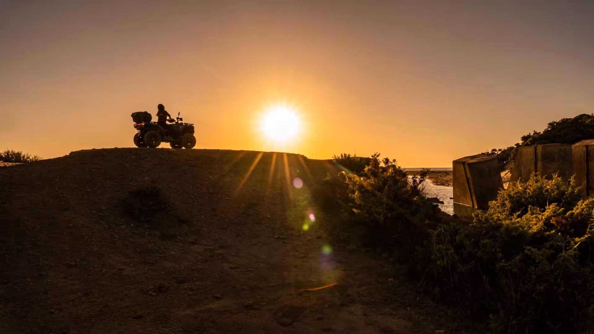 Silhouette of ATV rider at sunset on Arbus dunes, capturing the essence of adventure and natural beauty.